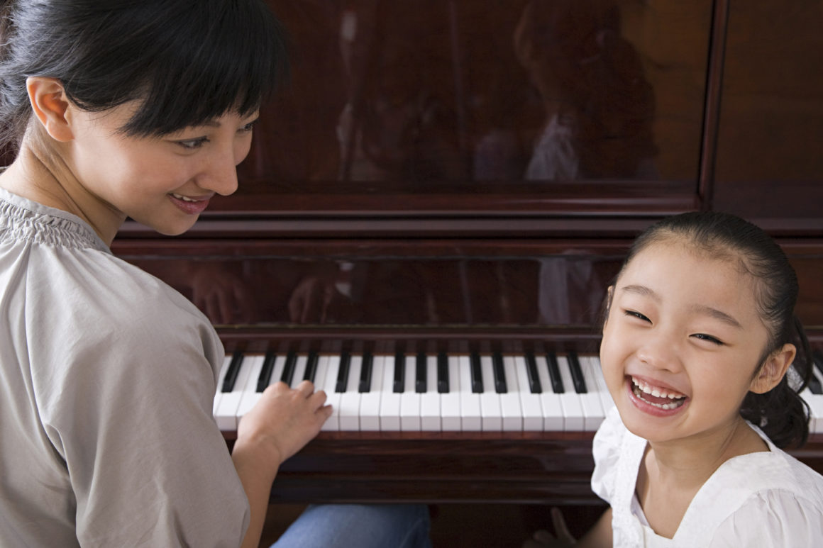A mother playing the piano for her daughter